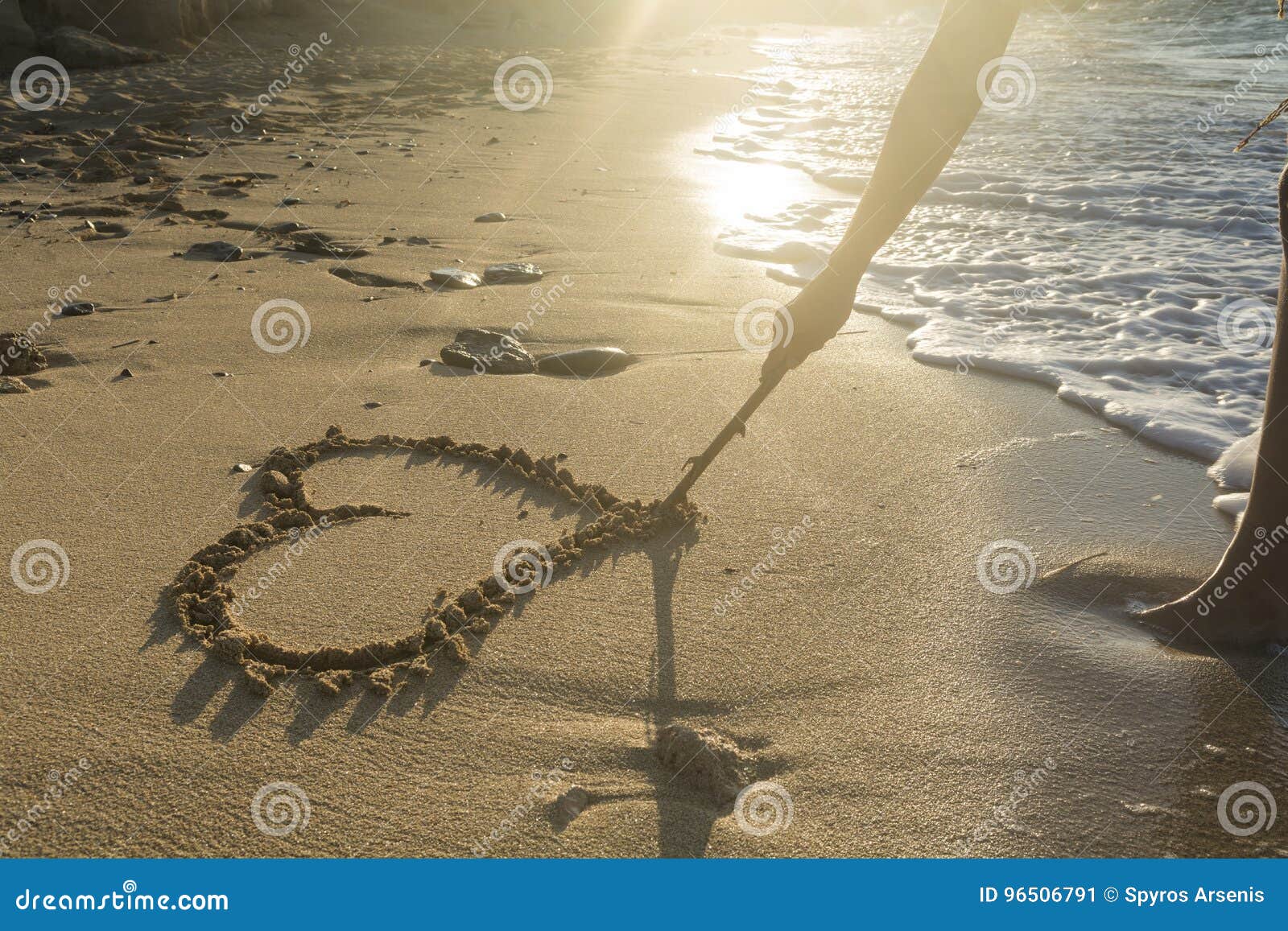 Ragazza che disegna un cuore sulla sabbia al tramonto in un amore di estate concentrato Immagine