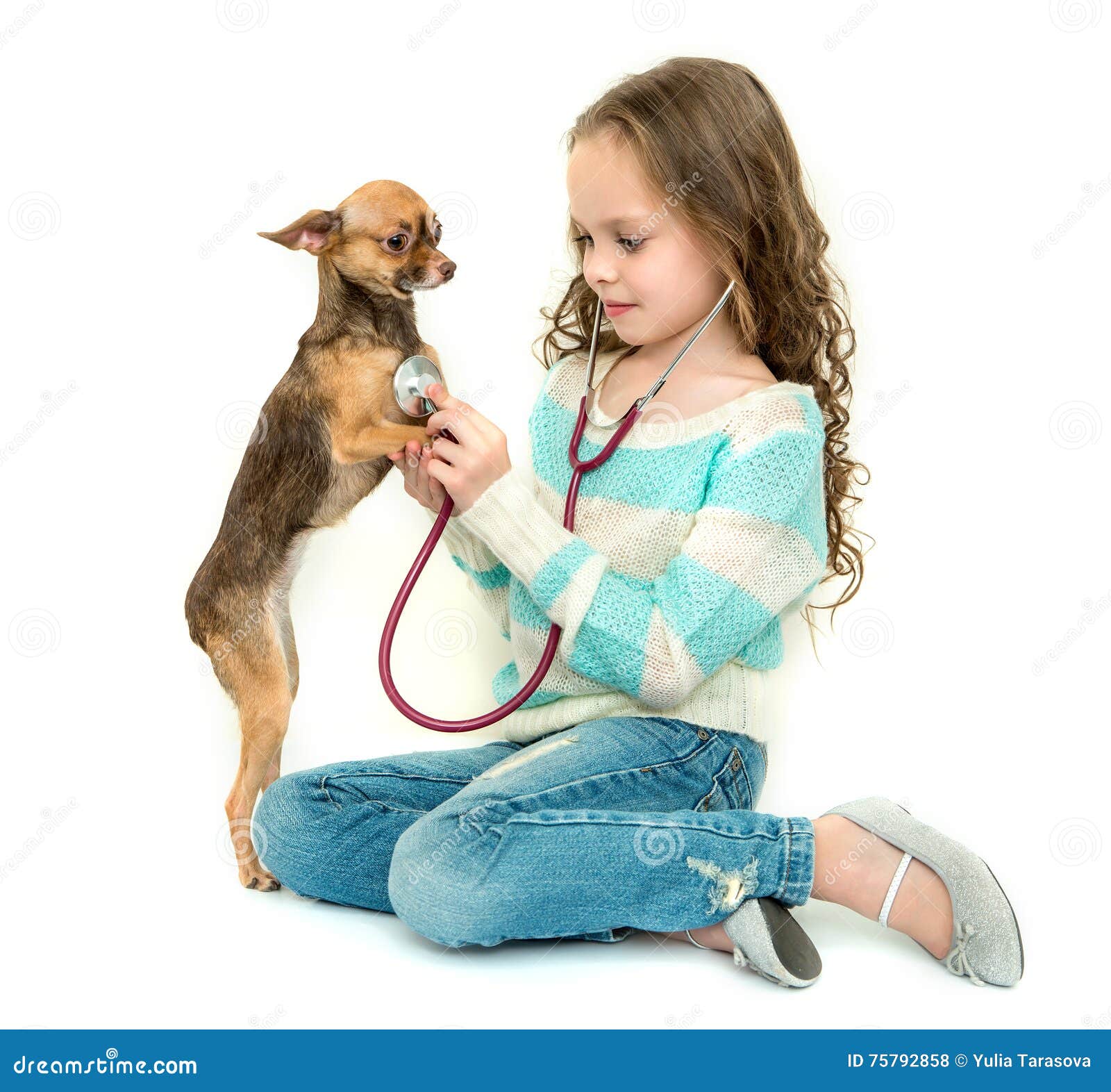 Ragazza del bambino che gioca veterinario con il suo piccolo cane, isolato su bianco