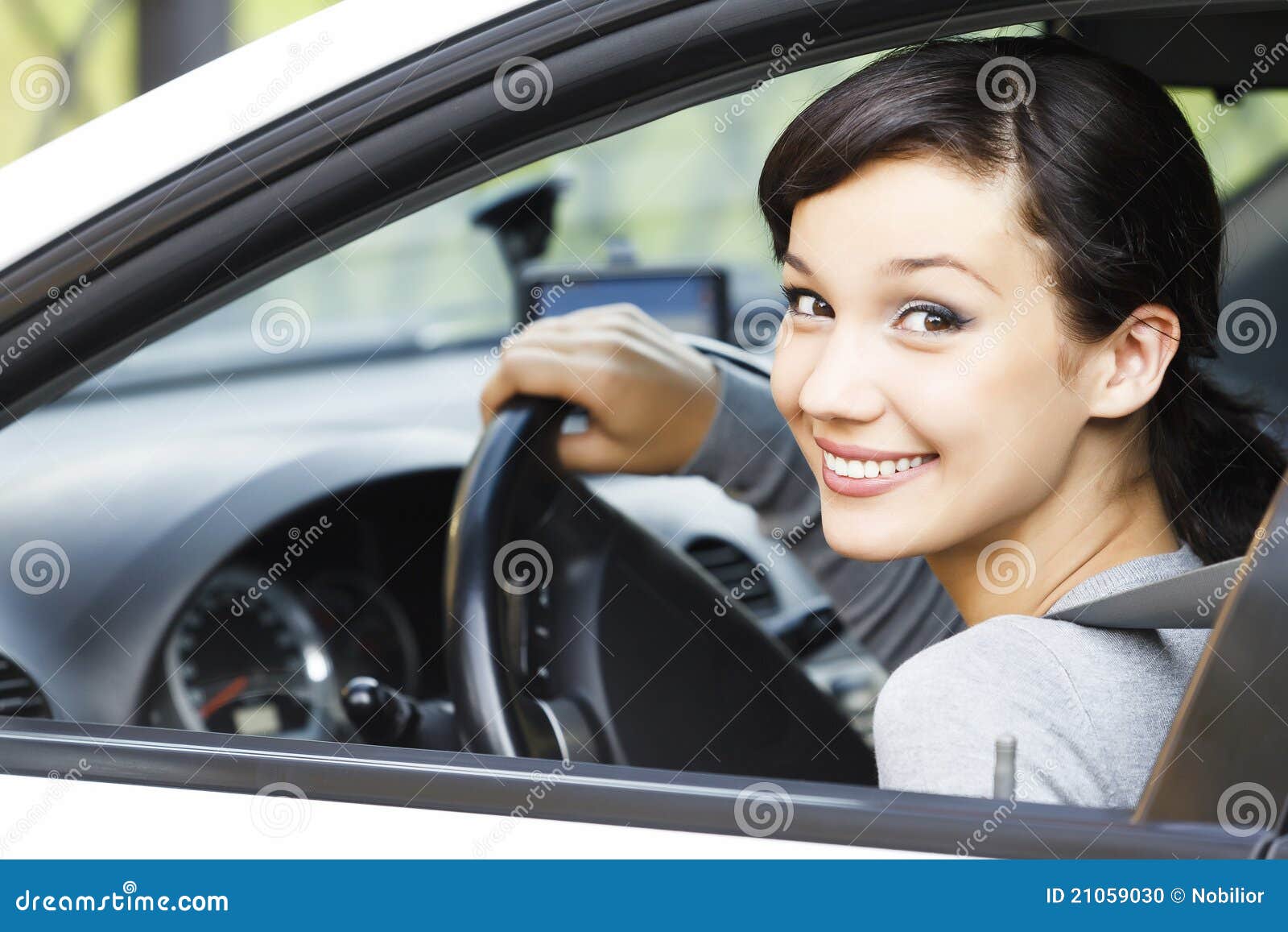 Ragazza graziosa in un'automobile che sorride a voi