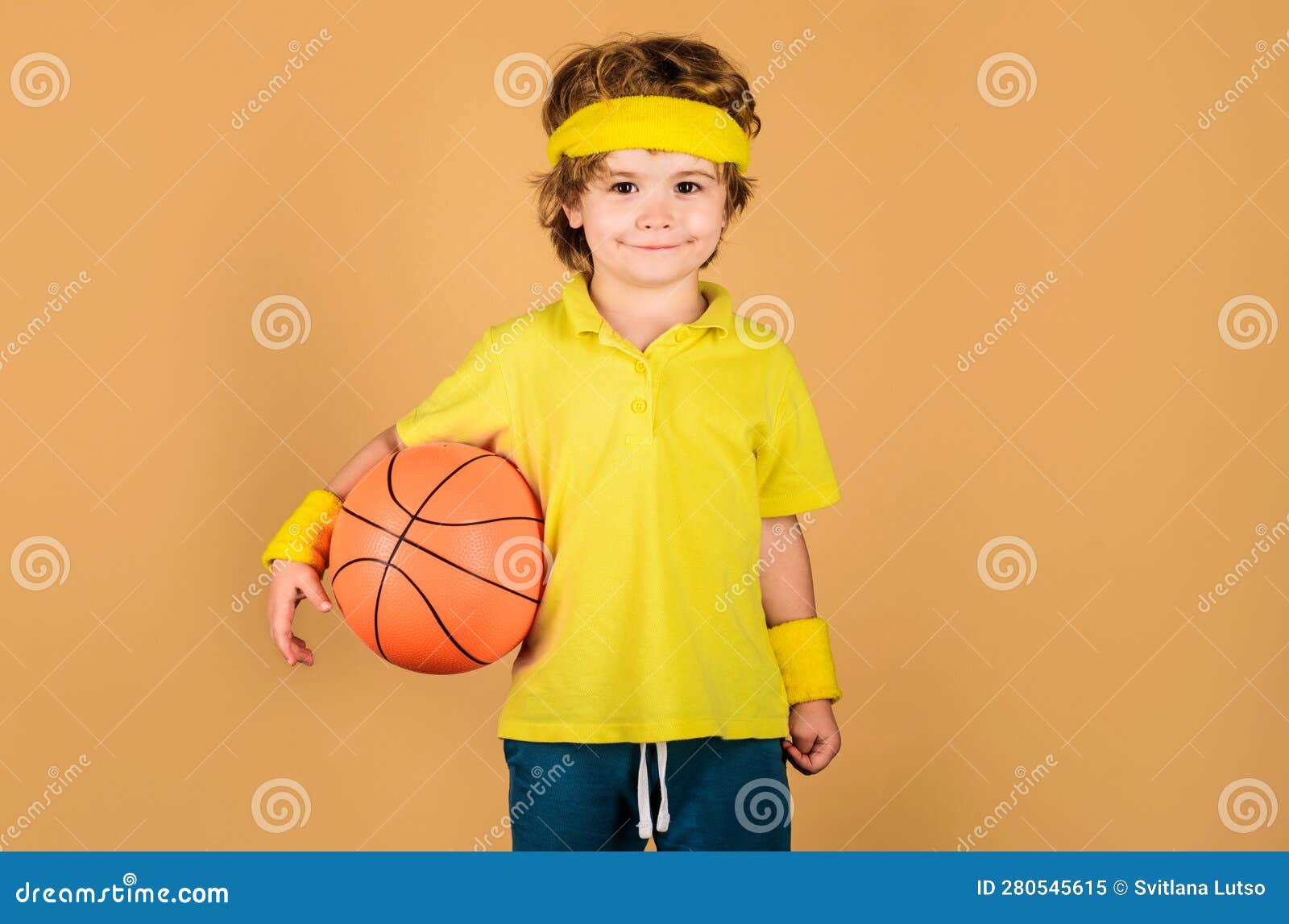 Gioco di allenamento di basket. Bambino sorridente con palla da basket che  mostra il pollice in