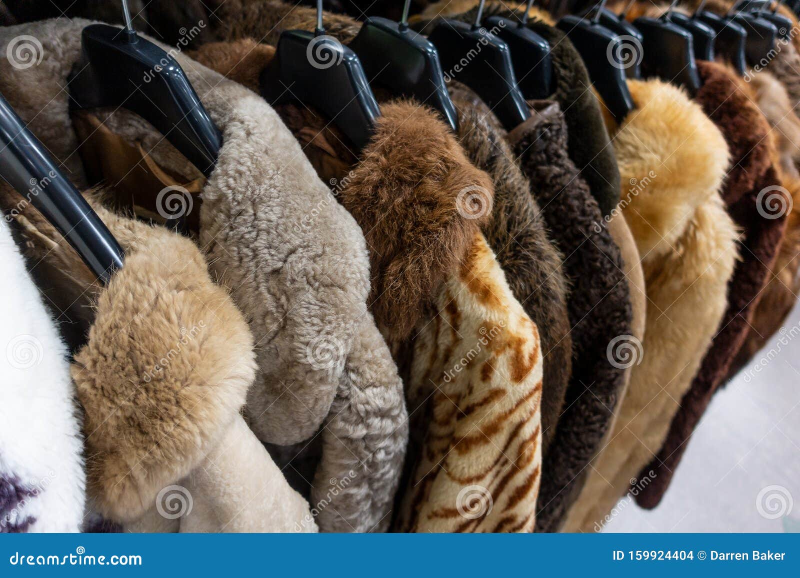 rail of secondhand fur coats for sale in a thrift store shop