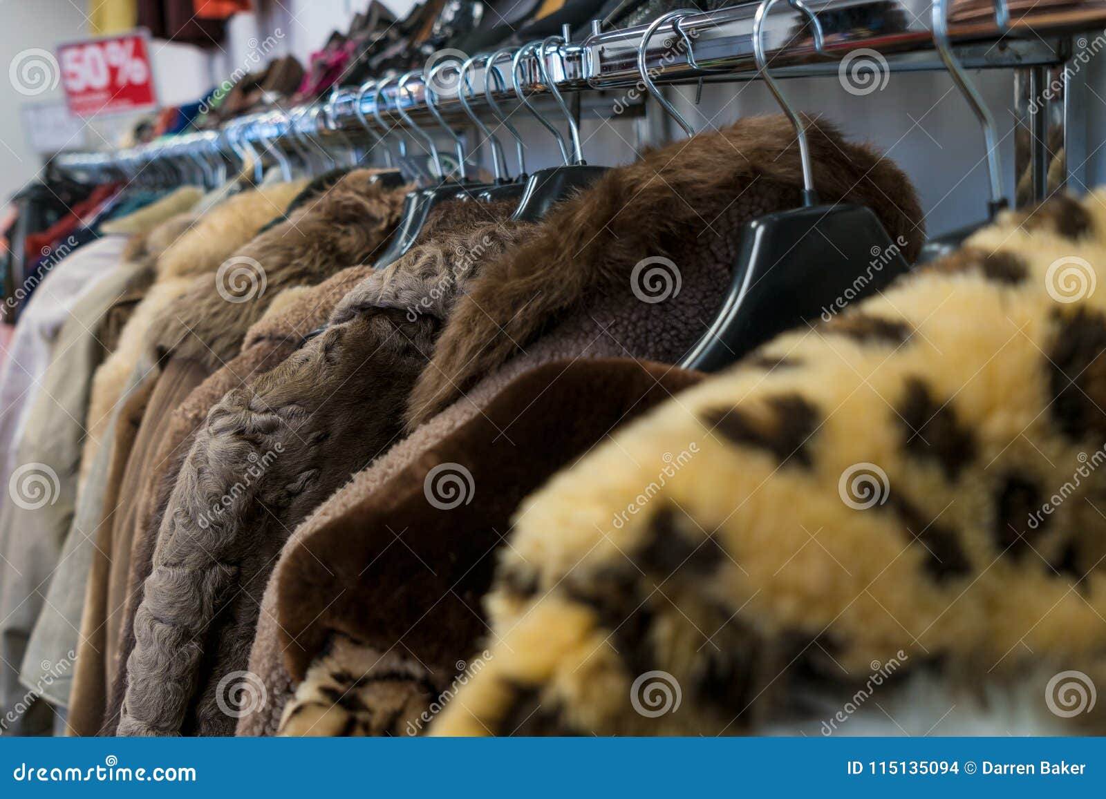 rail of secondhand fur coats for sale in a thrift store shop
