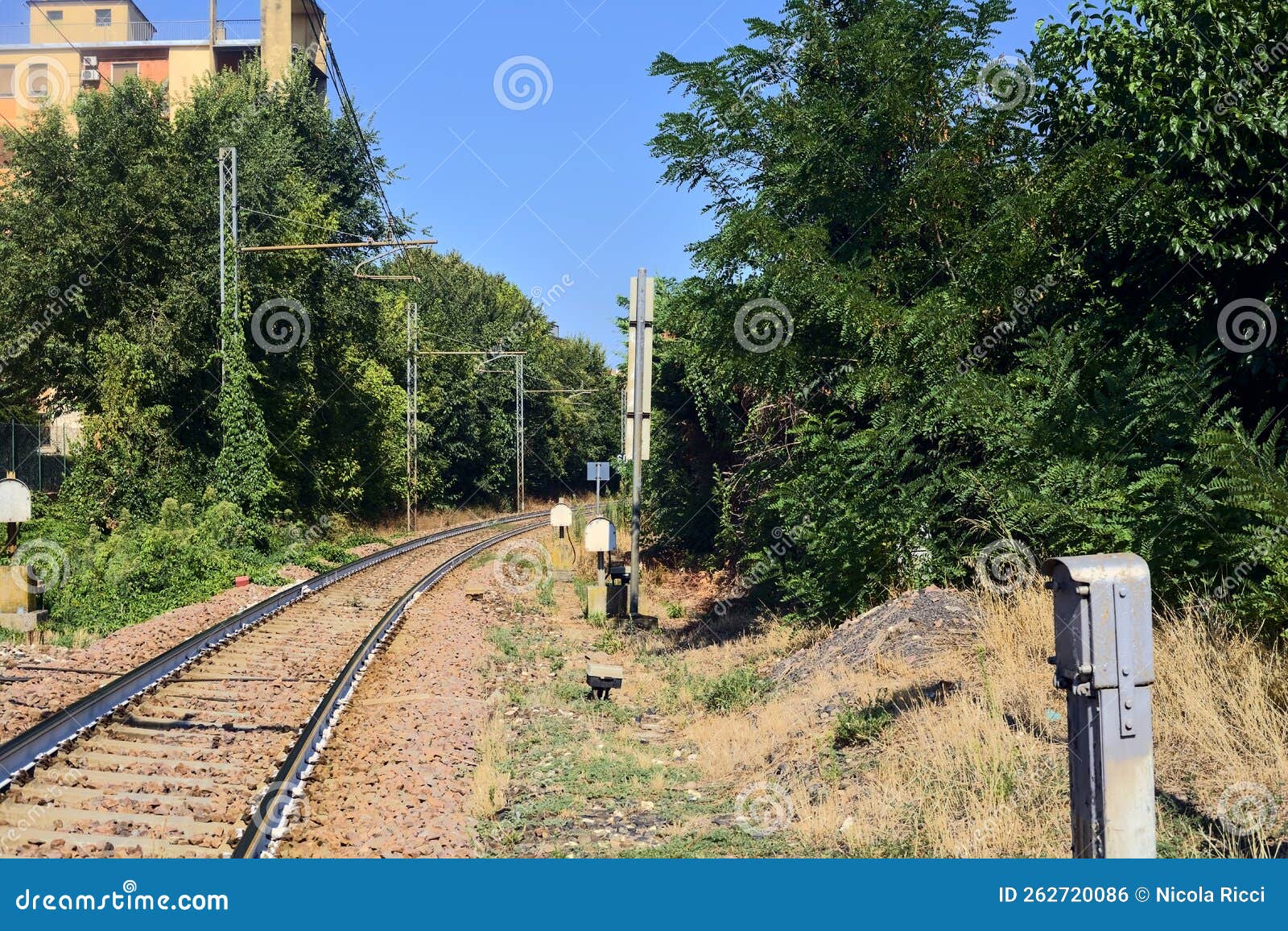Railroad Crossing with Trees and Buildings by Its Side at Sunset Stock
