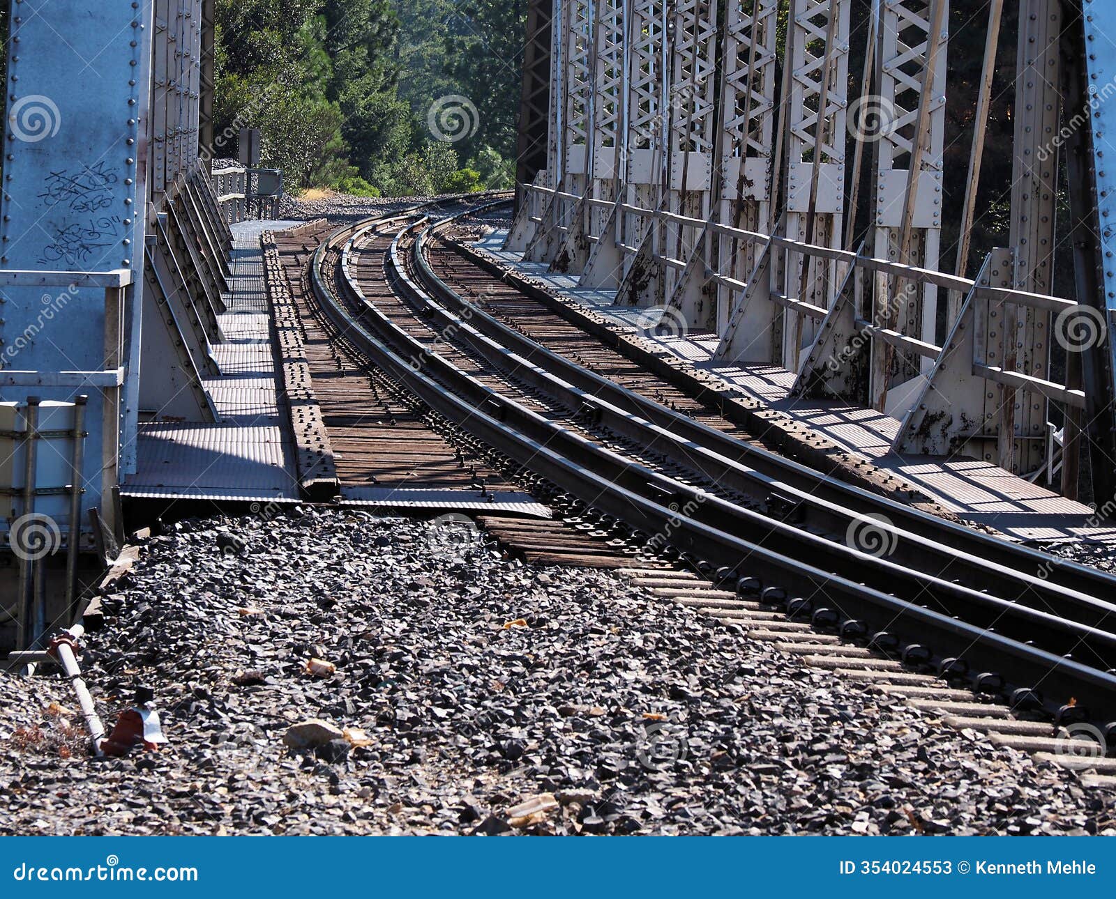 railroad tracks are seen on a bridge from nearly ground level.