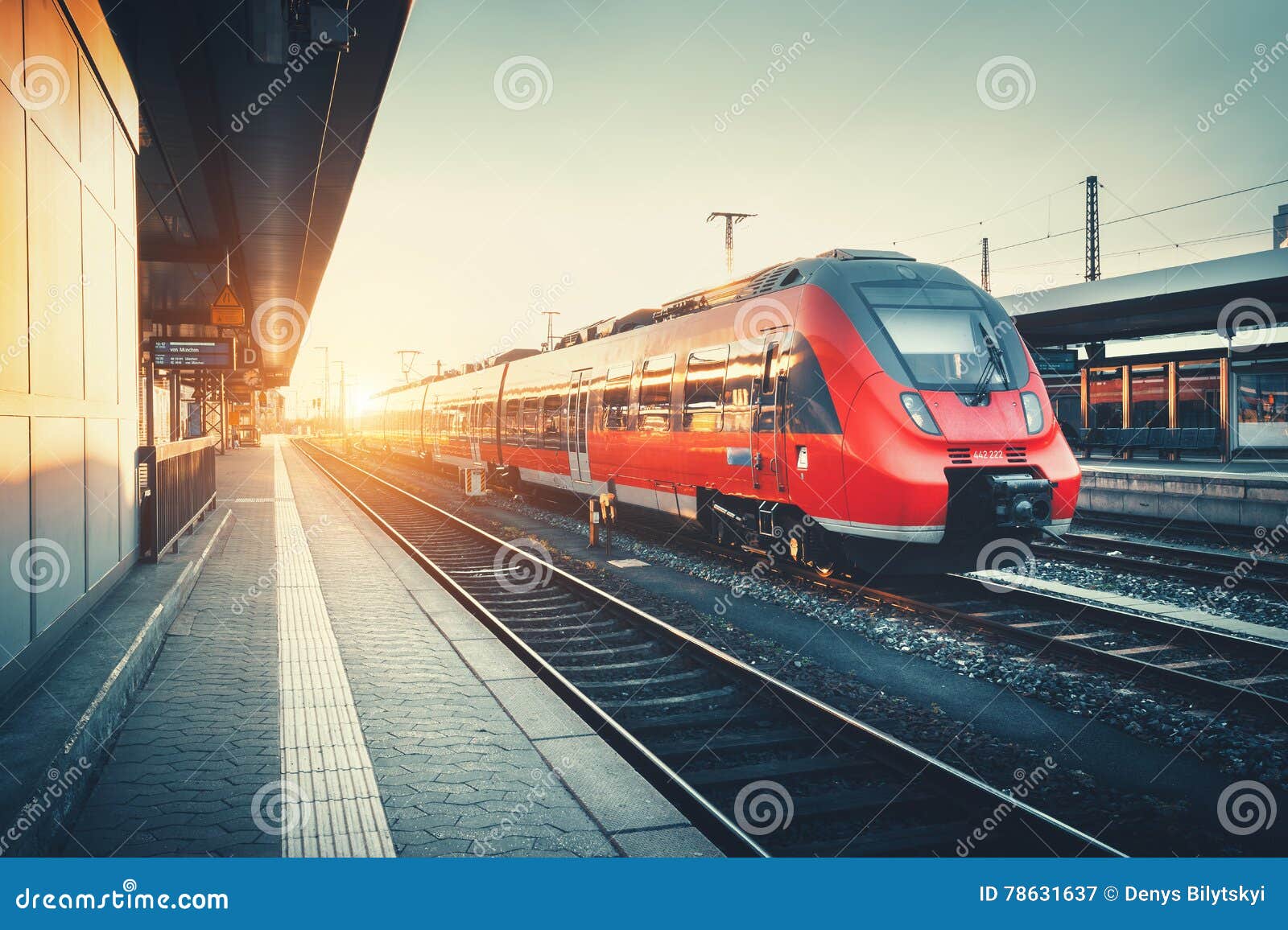 railway station with beautiful modern red commuter train at suns