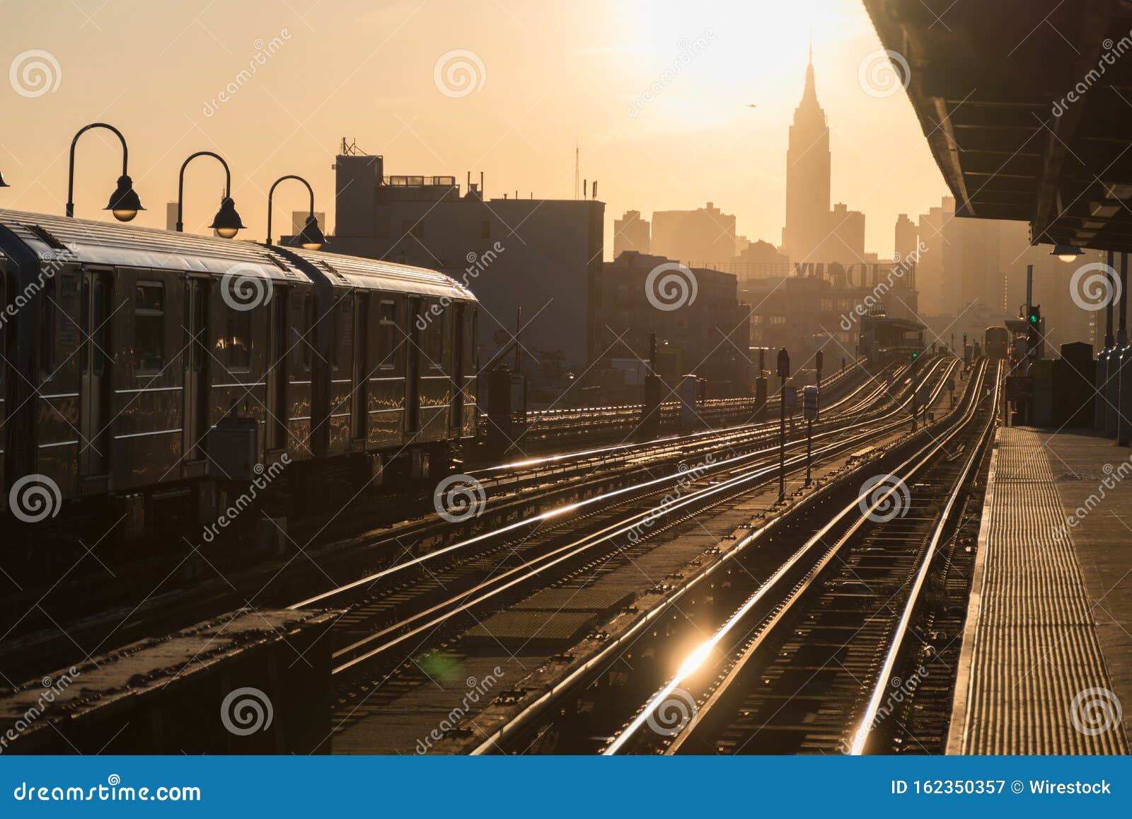 railway station platform with trains coming and leaving and a city silhouette in the background