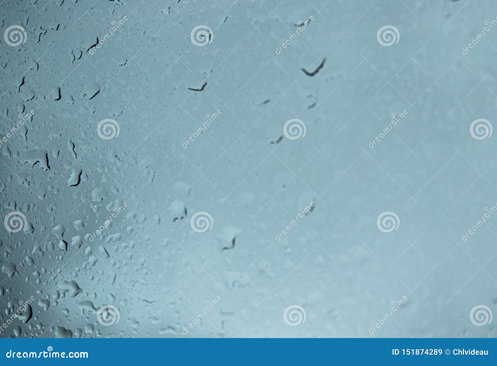 rain drops on window against grey cloudy background