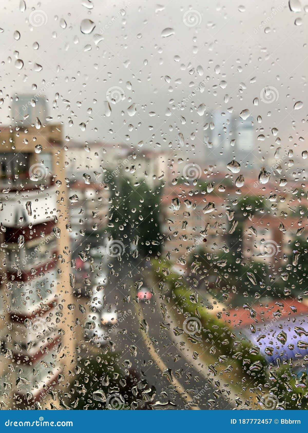 rain drops on a window pane against city view