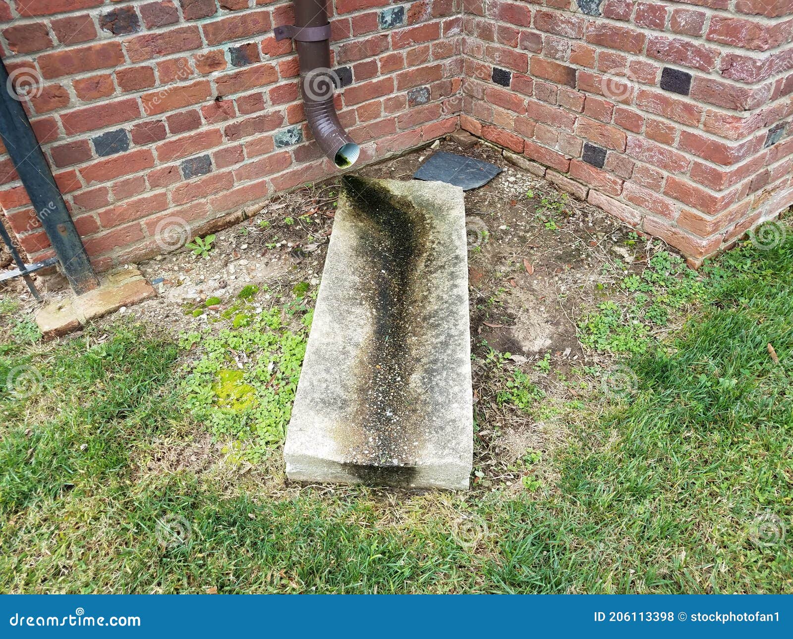 Rain Gutter Downspout and Cement Slab with Brick Wall Stock Photo