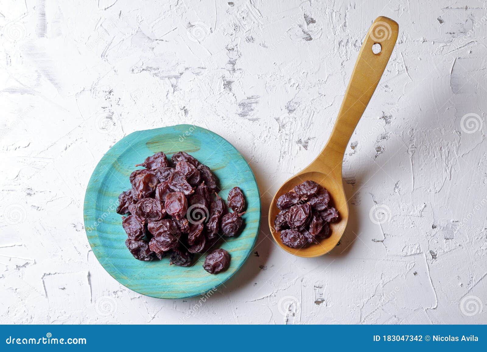 raisins on aquamarine plate and brown wooden spoon