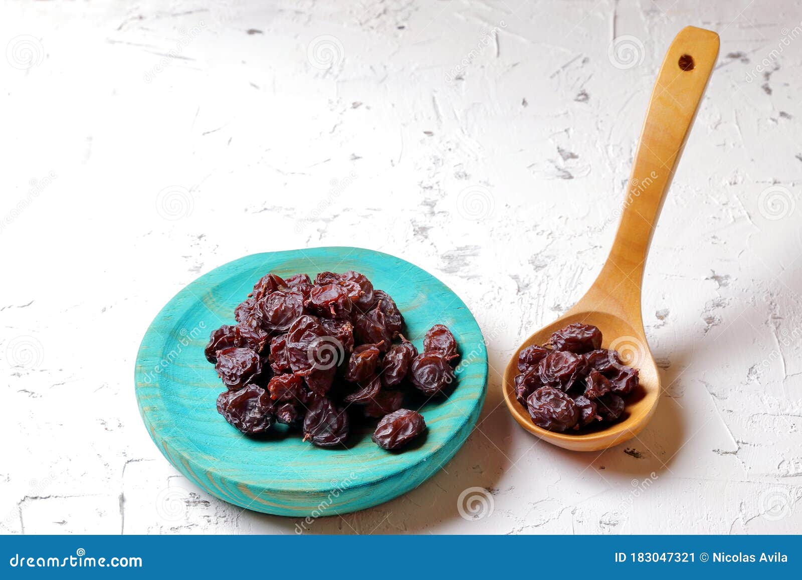 raisins on aquamarine plate and brown wooden spoon