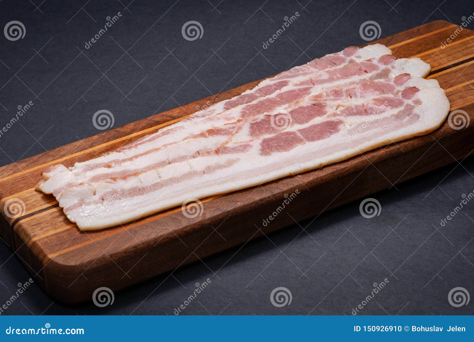 rashers of uncured apple smoked bacon arranged on natural wooden cutting board
