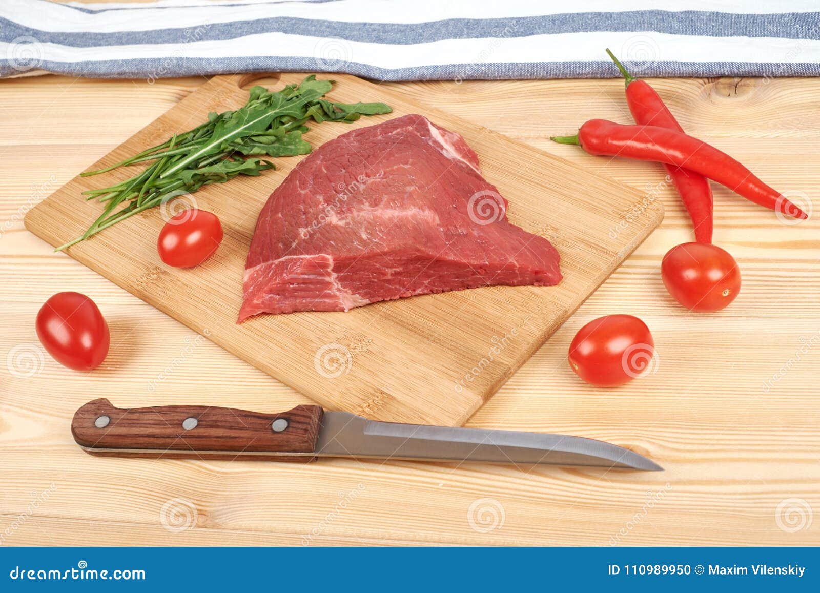 Raw Beef Meat on Cutting Board with Vegetables on a Wooden Background