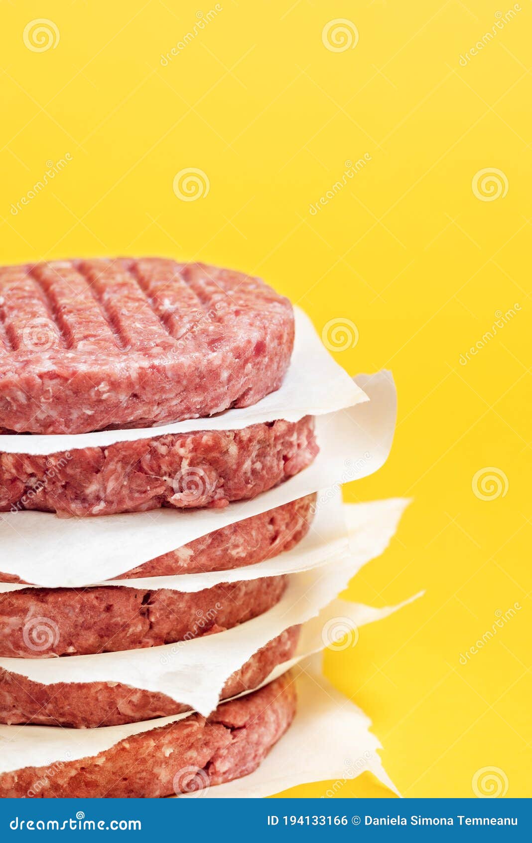 Raw Beef Patties in a Stack Isolated on a Yellow Background. Hamburger
