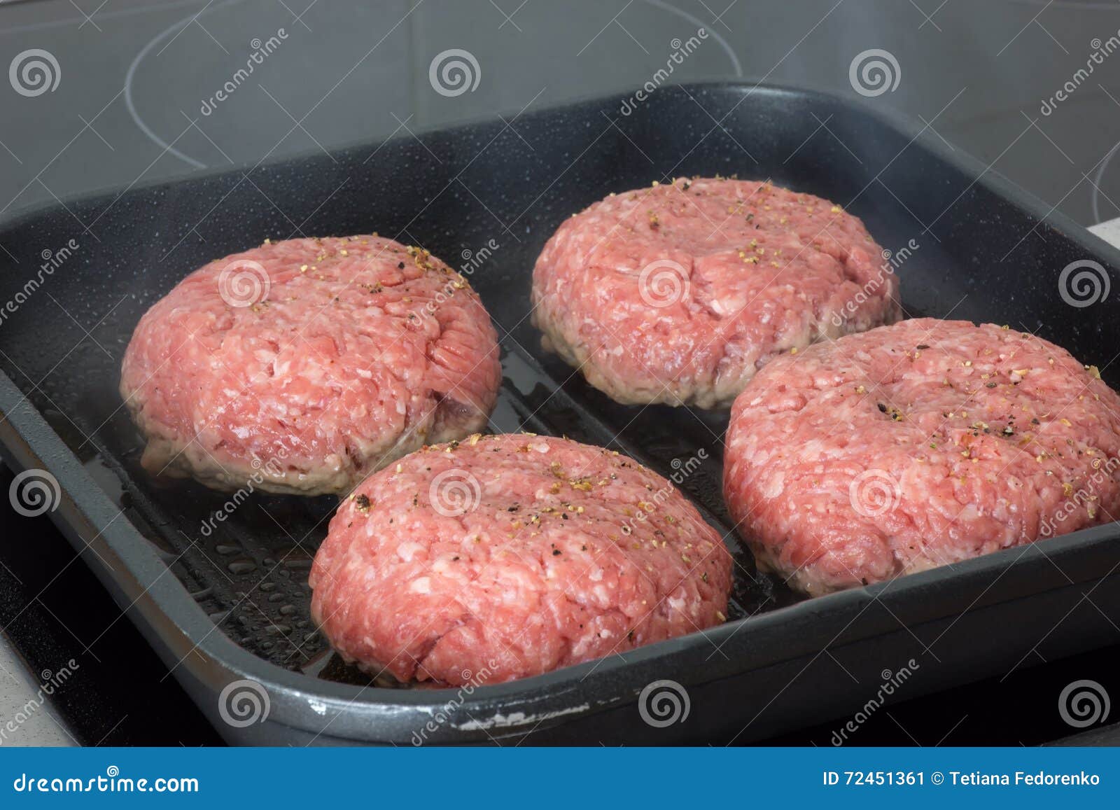 Raw Burgers, Beef in a Frying Pan on Cooking Surface in Kitchen Stock