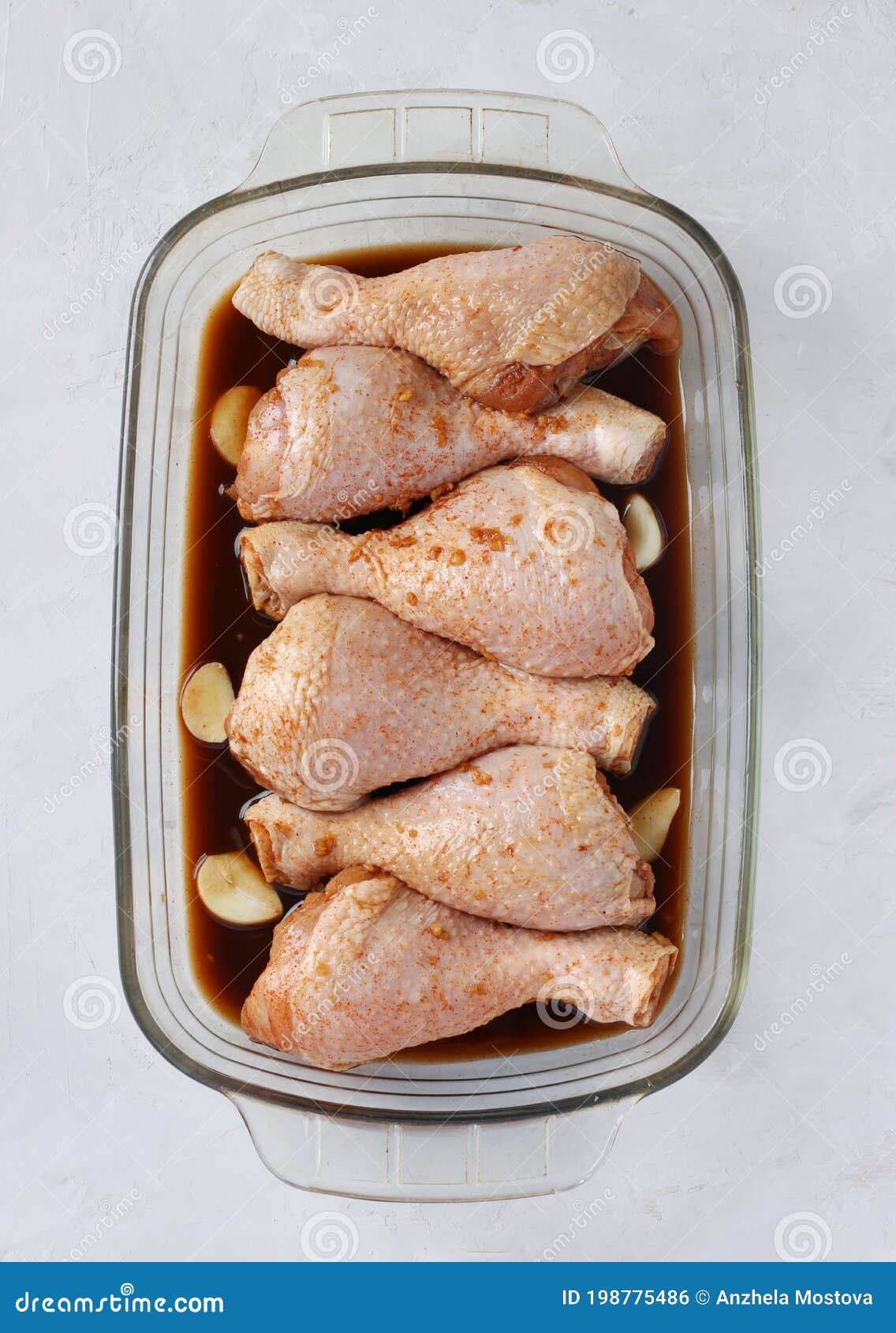 Raw Chicken Drumsticks in Soy Sauce with Garlic in a Mold before Baking