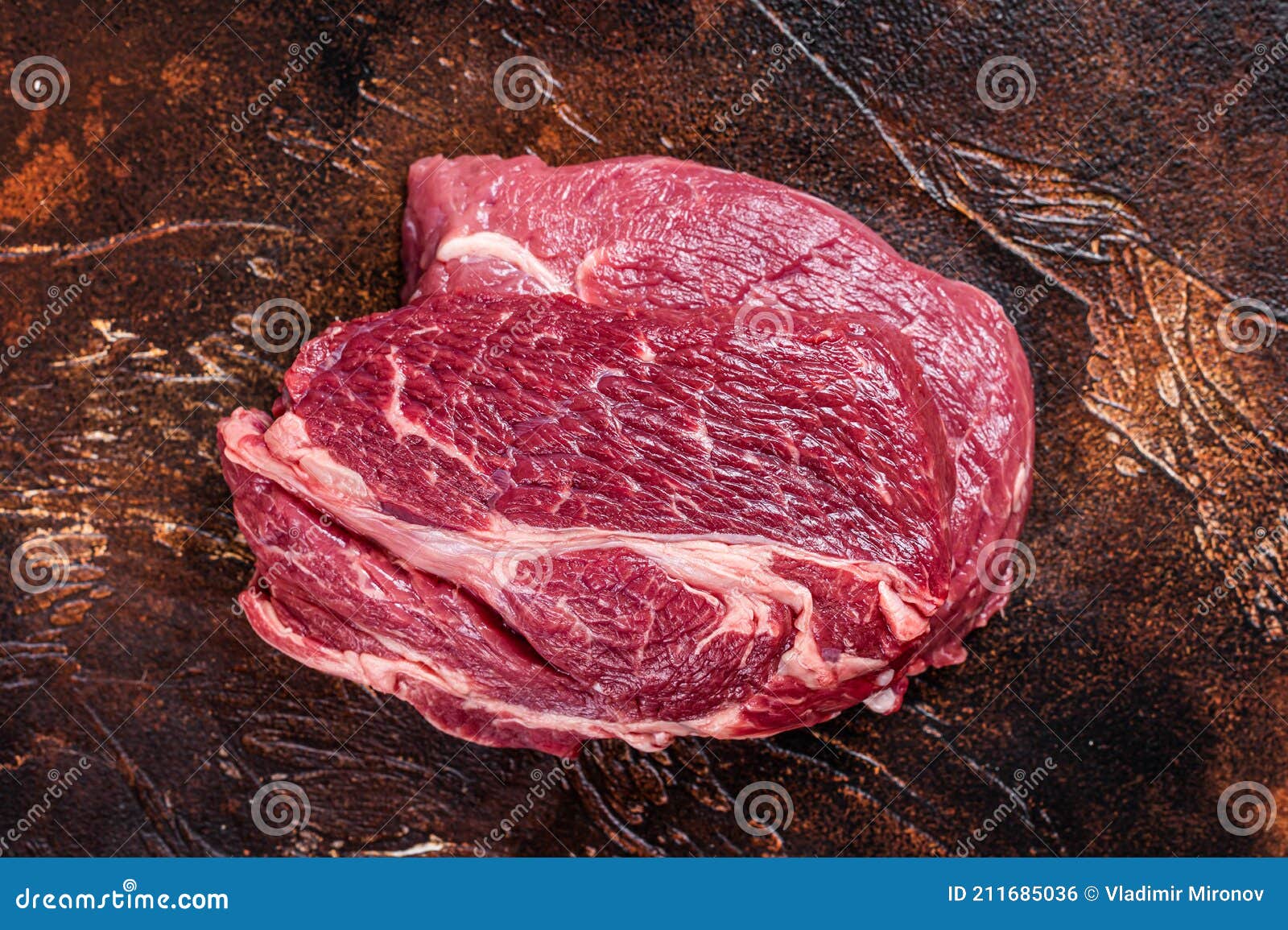 Raw Chuck Eye Roll Beef Steak on Butcher Table. Dark Background Stock