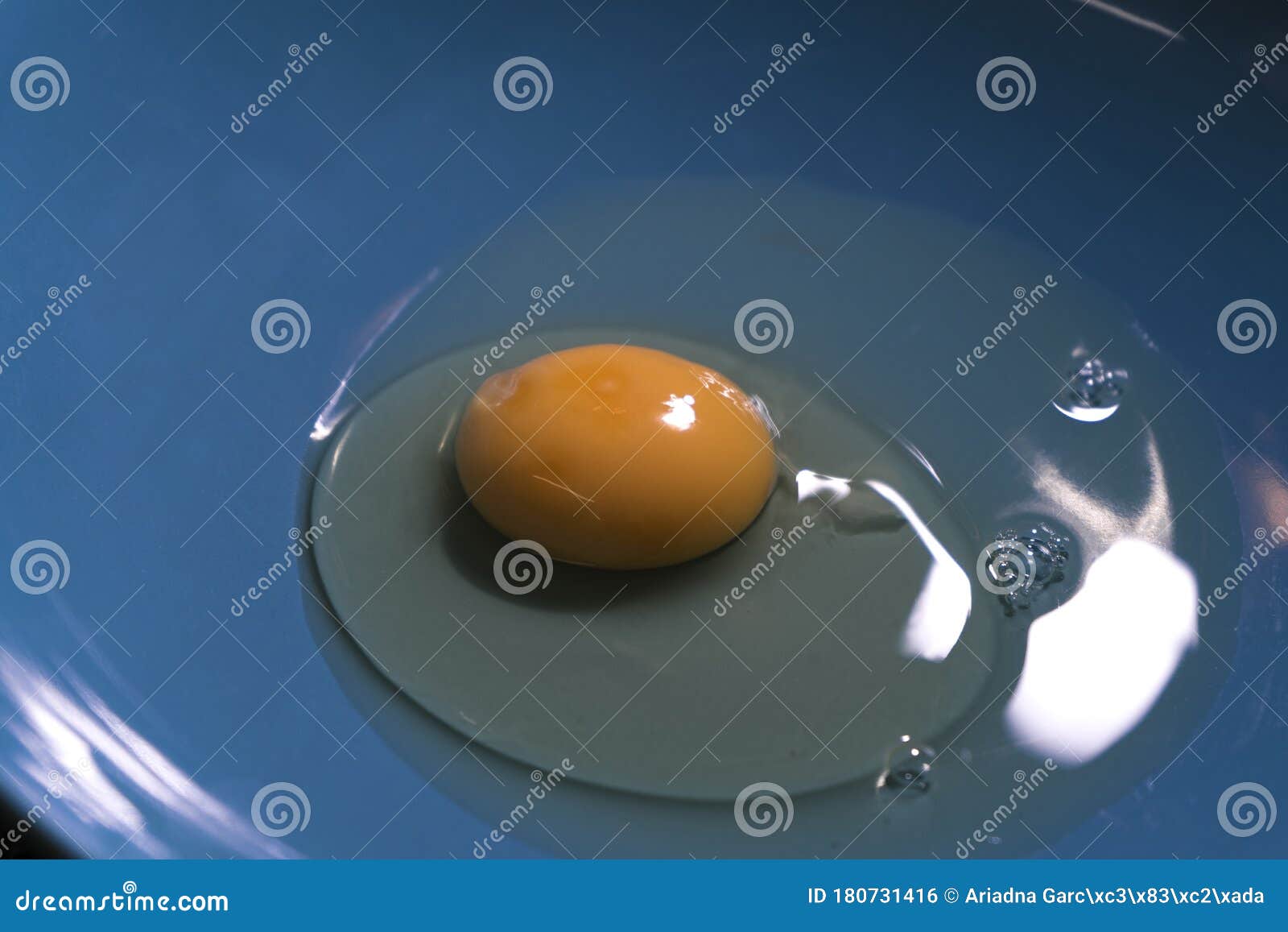 a raw egg inside a blue plate.