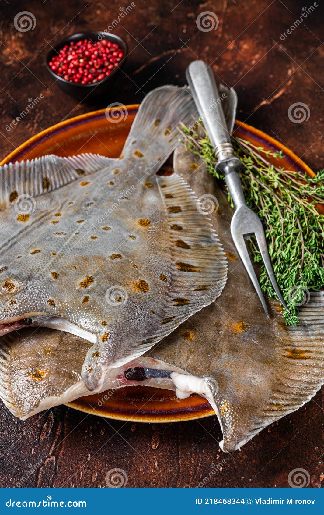 Raw Flounder or Plaice on Rustic Plate with Herbs. Dark Background