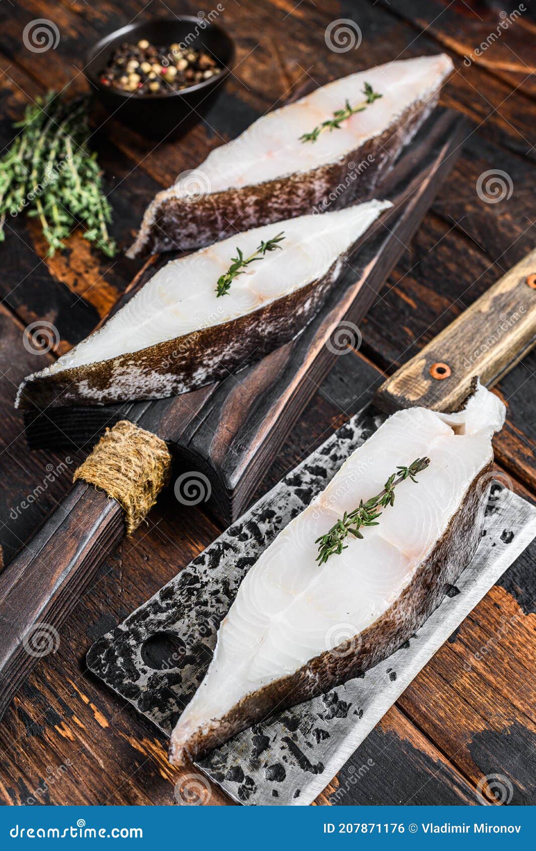 raw fresh halibut fish steak on a wooden cutiing board. black background. top view