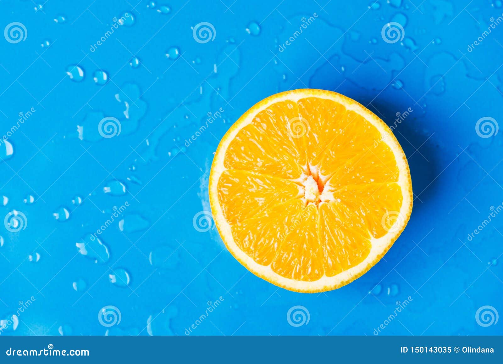 raw juicy citrus fruit cut in half orange on wet blue background with water drops splashes. summer beverages refreshments drinks