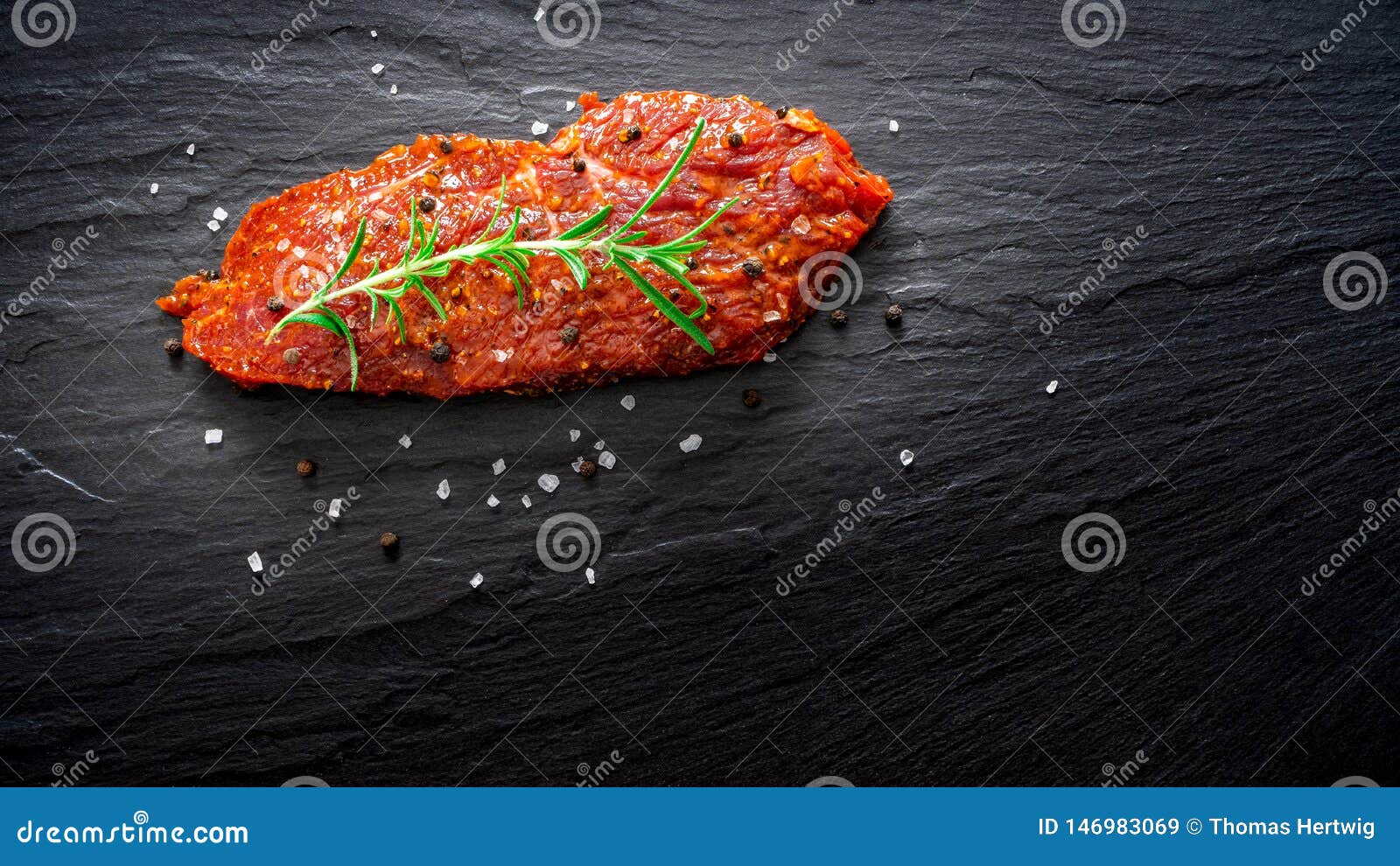 raw marinated meat, beef steak on black slate background, top view