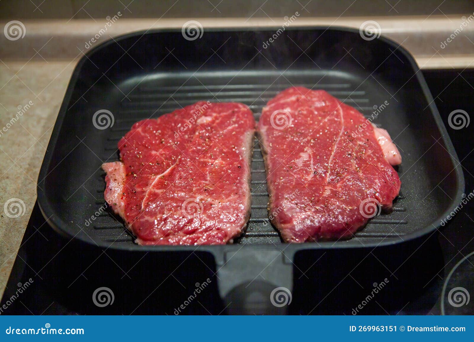 Raw Minute Steak of Marbled Beef in a Grill Pan on an Electric Cooking Surface Stock Image