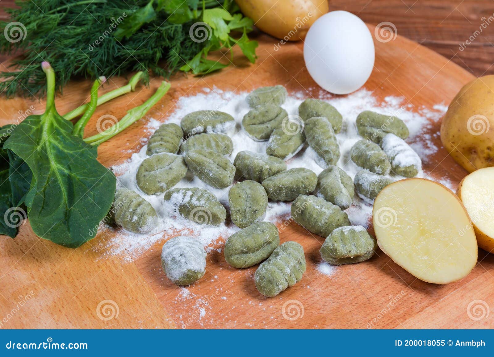 raw potato gnocchi with spinach in flour on wooden board