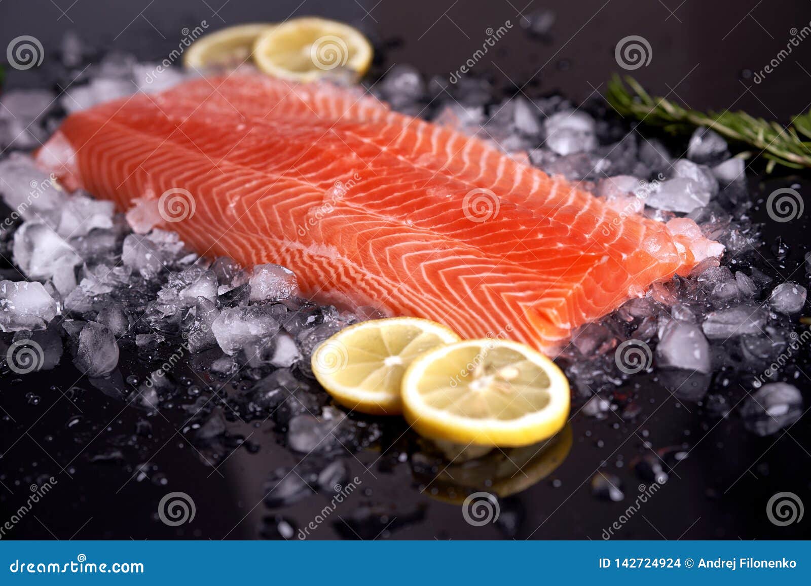 fillet of red fish at 45 degrees lying on a dark background with slices of lemon, rosemary and green chili. view from above. shall