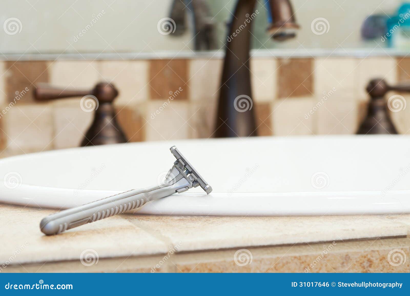 Razor Resting On Edge Of Sink In Bathroom Stock Photo