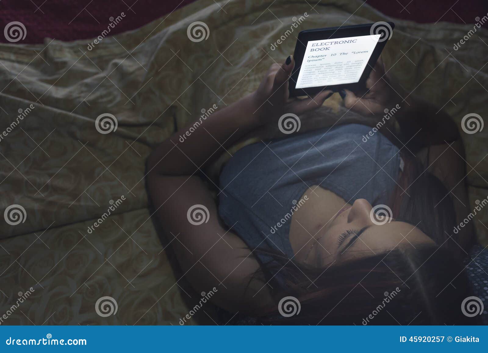 Reading an ebook in bed stock image. Image of ereader 45920257