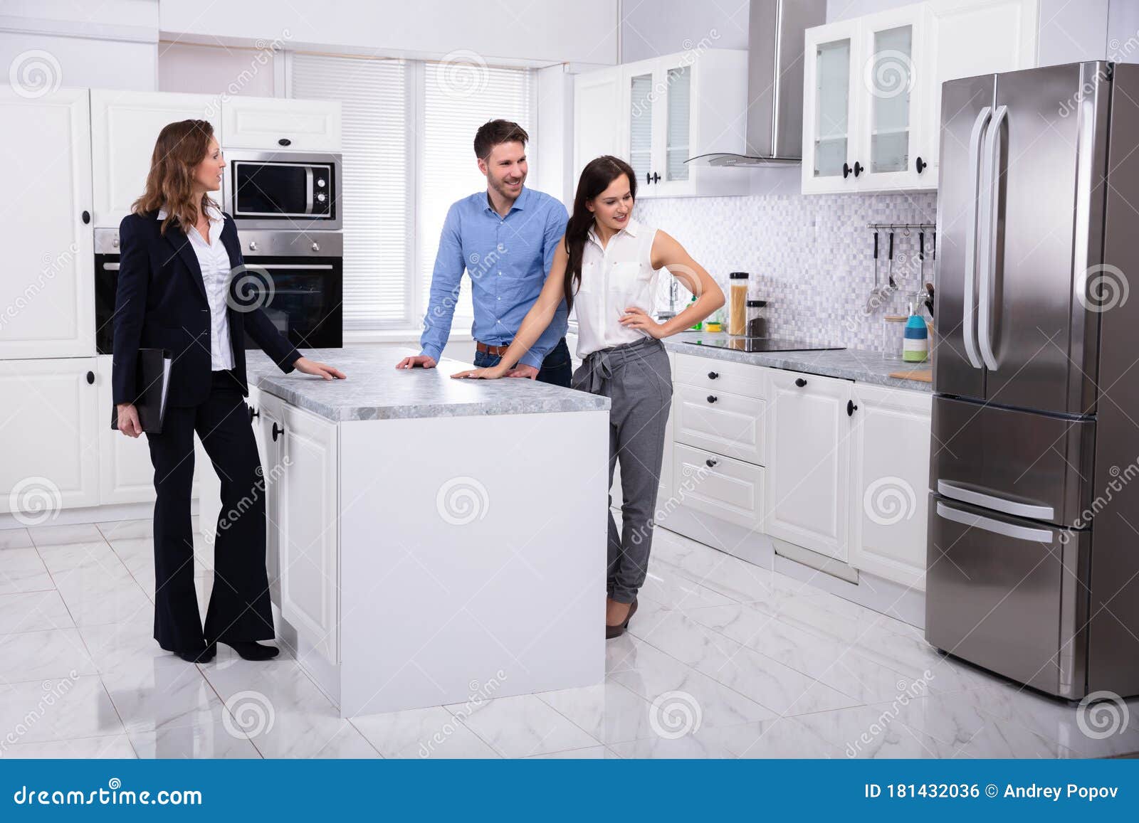 real estate agent showing refrigerator in house to a couple