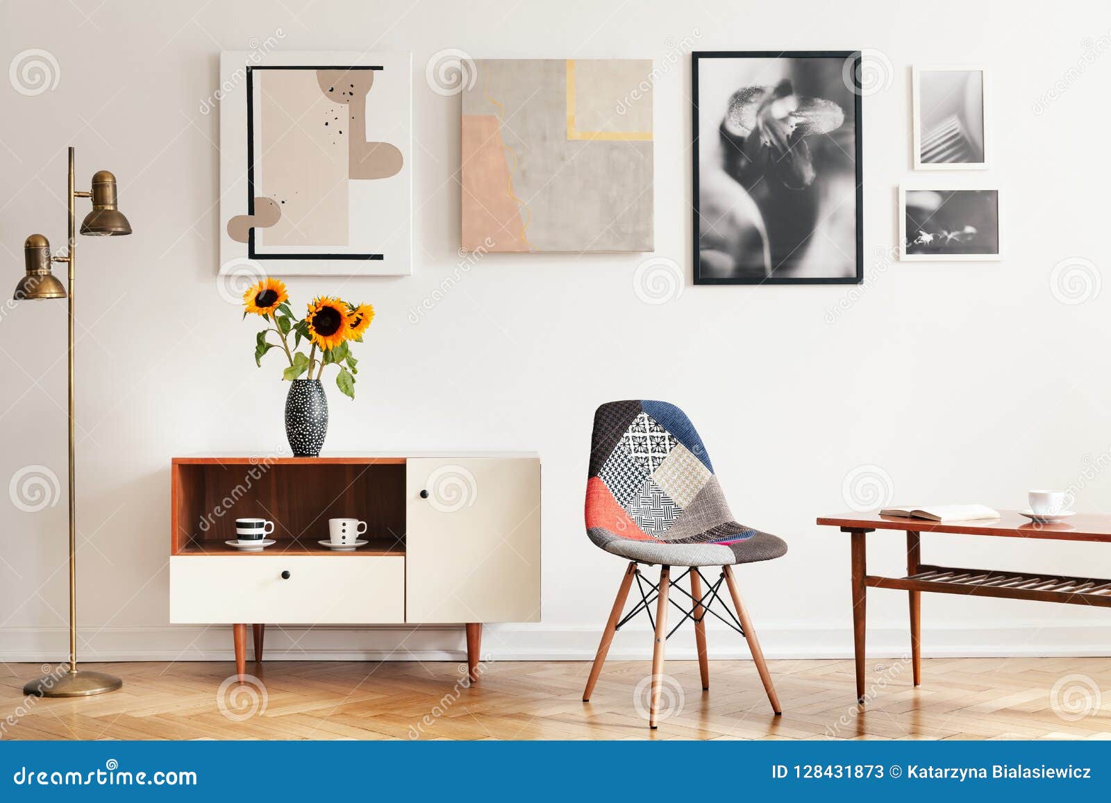 real photo of bright eclectic living room interior with many posters, colorful chair, wooden cupboard with flowers and coffee tabl