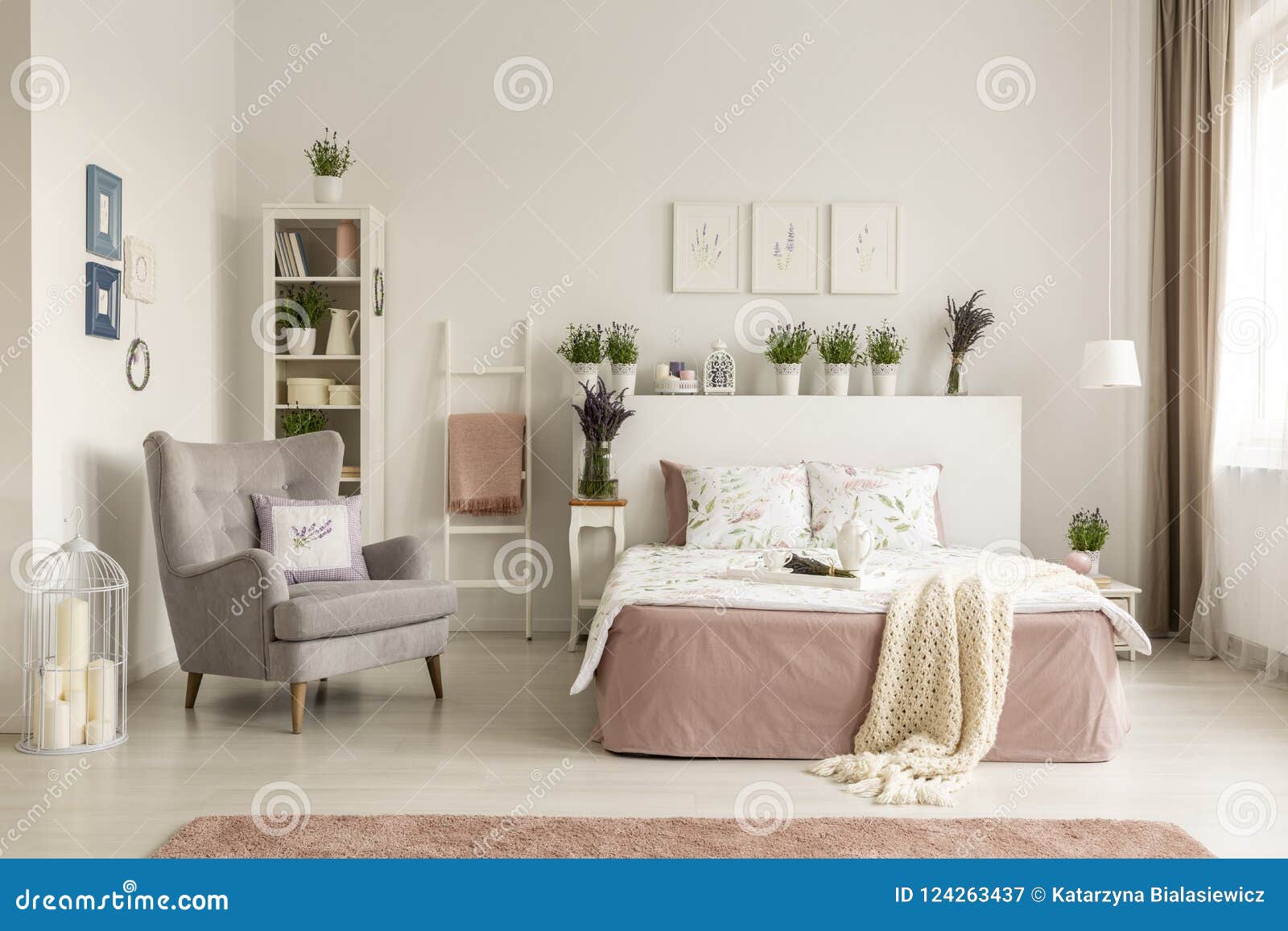 real photo of a feminine bedroom interior with a comfy armchair, bed, plants and shelf