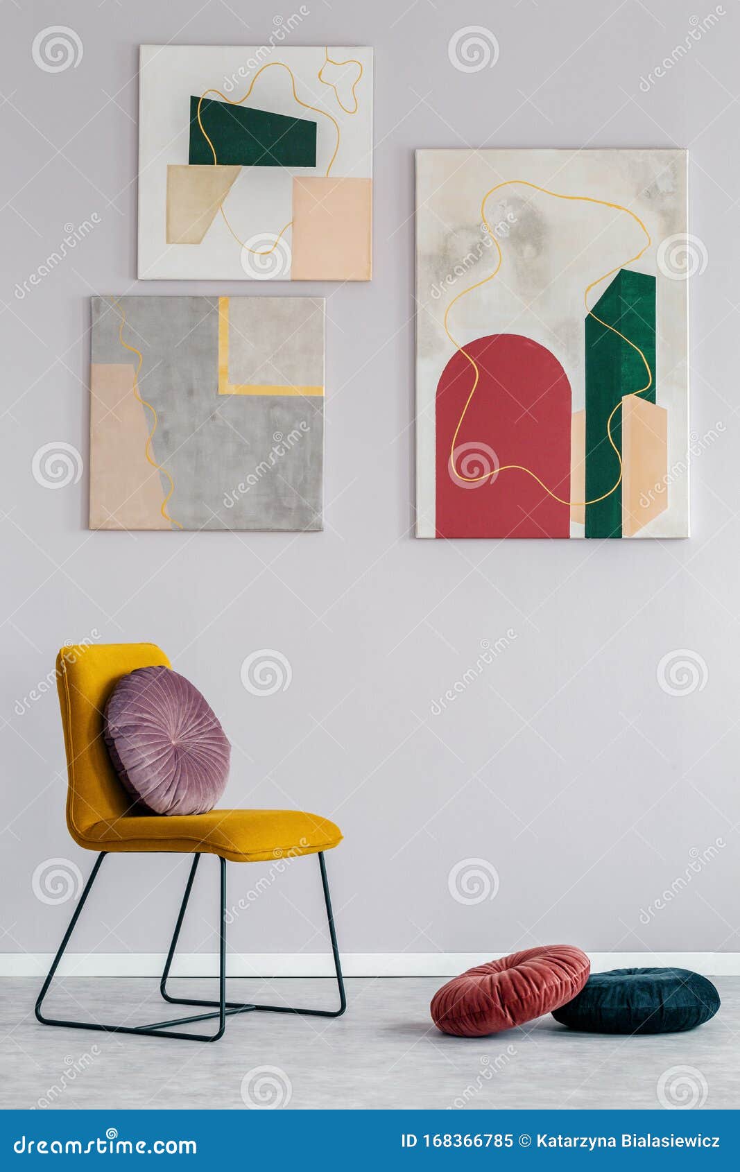 gray living room interior with a set of modern paintings on the wall and a velvet cushion on a yellow chair