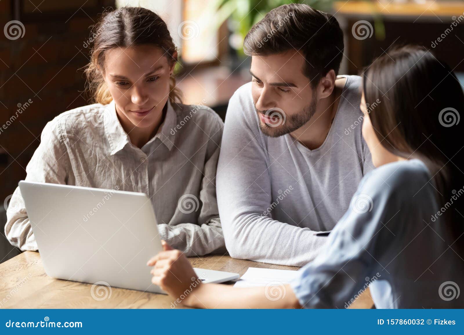 realtor or insurance broker consulting young couple in cafe