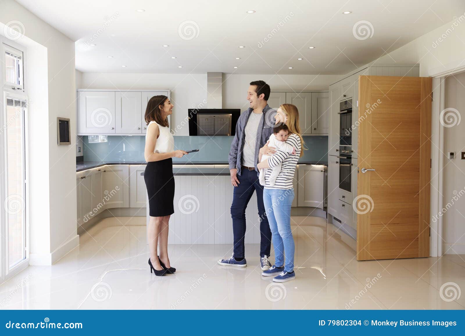 realtor showing young family around property for sale