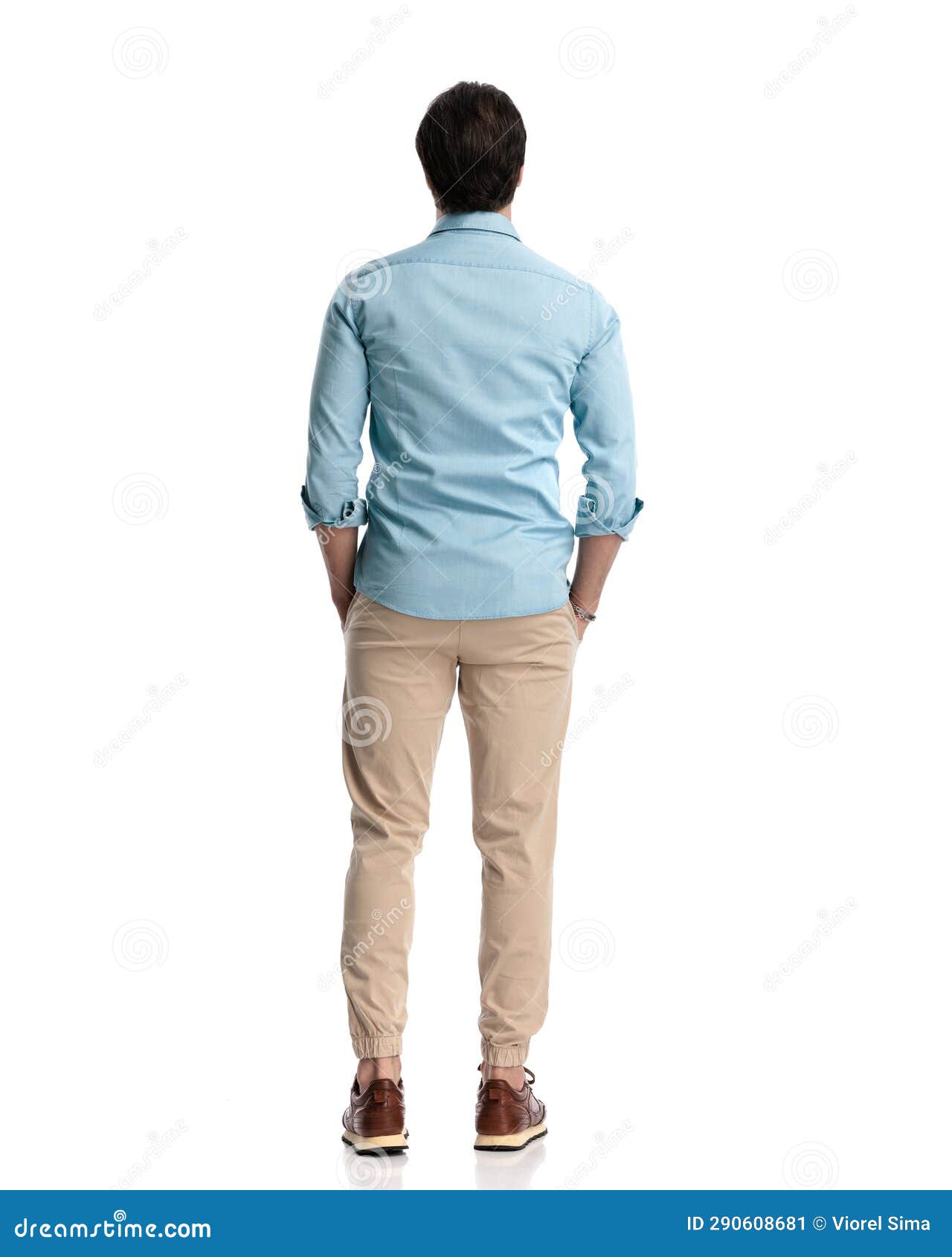 rear view of casual man in denim shirt with chino pants holding hands in pockets