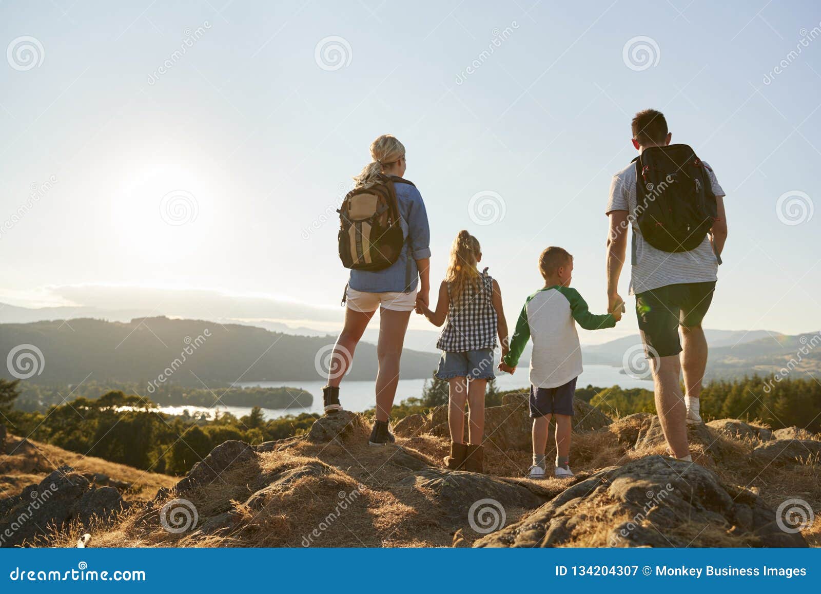 rear view of family standing at top of hill on hike through countryside in lake district uk