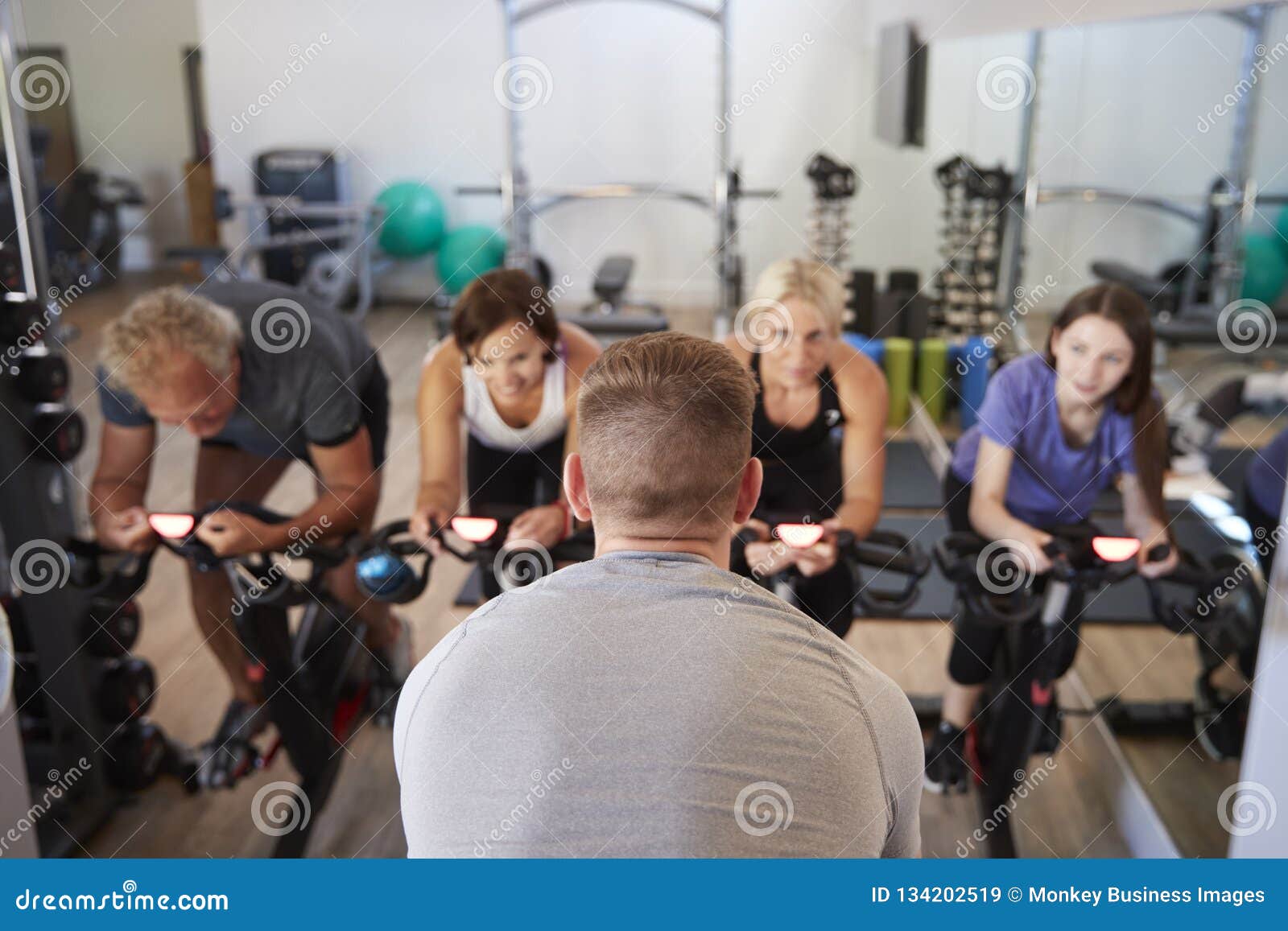 rear view of male trainer taking spin class in gym