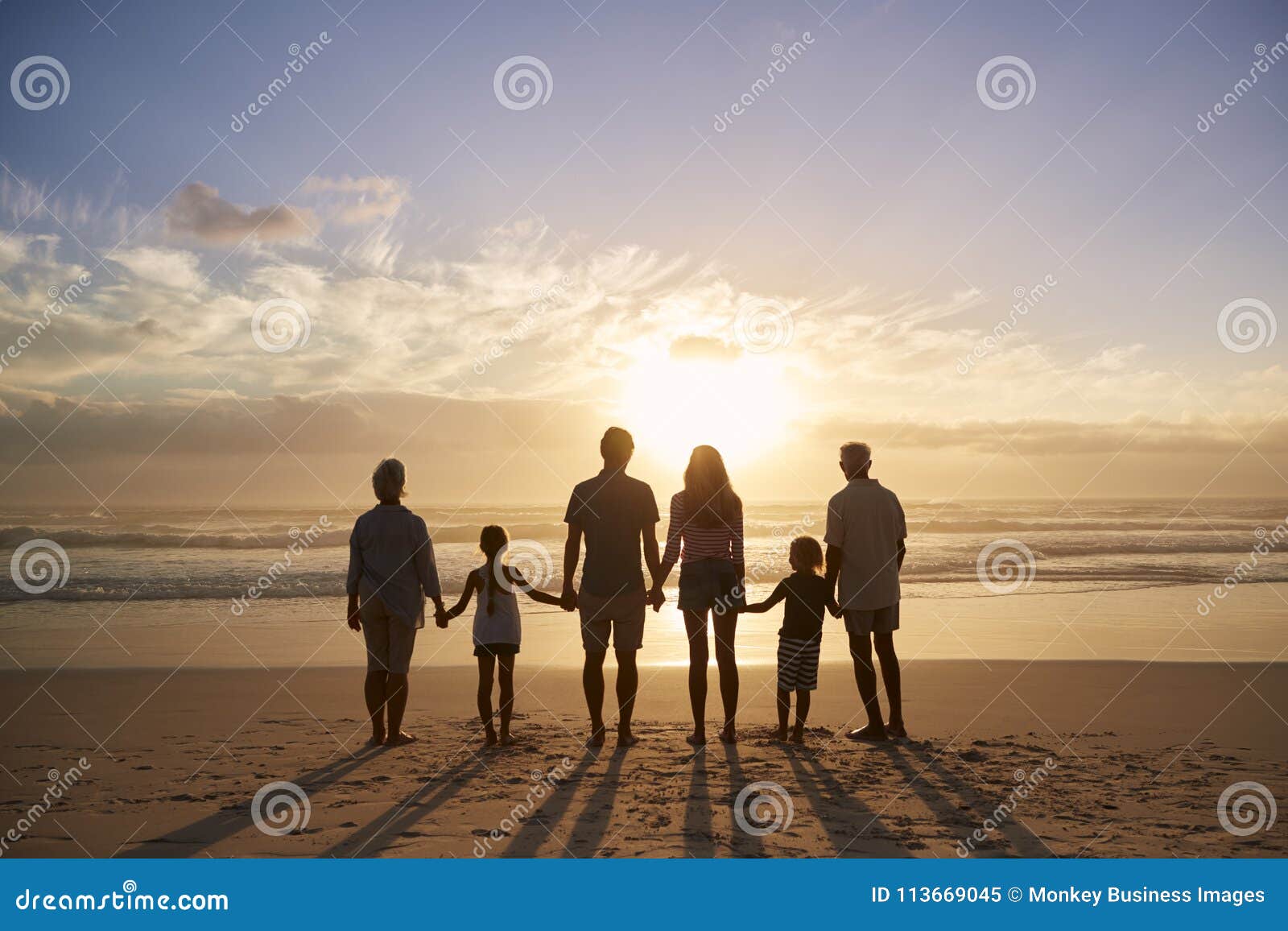 rear view of multi generation family silhouetted on beach