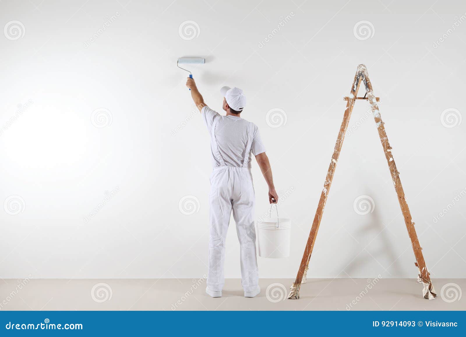 rear view of painter man painting the wall, with paint roller an