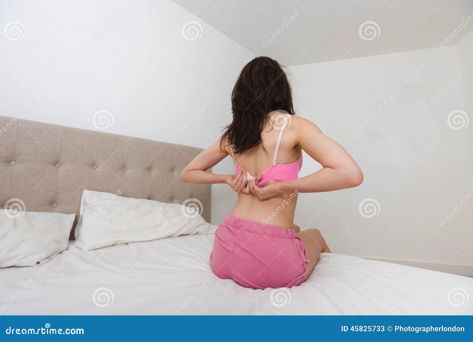 Rear View of Woman Fastening Bra in Bed Stock Image - Image of space,  frame: 45825733