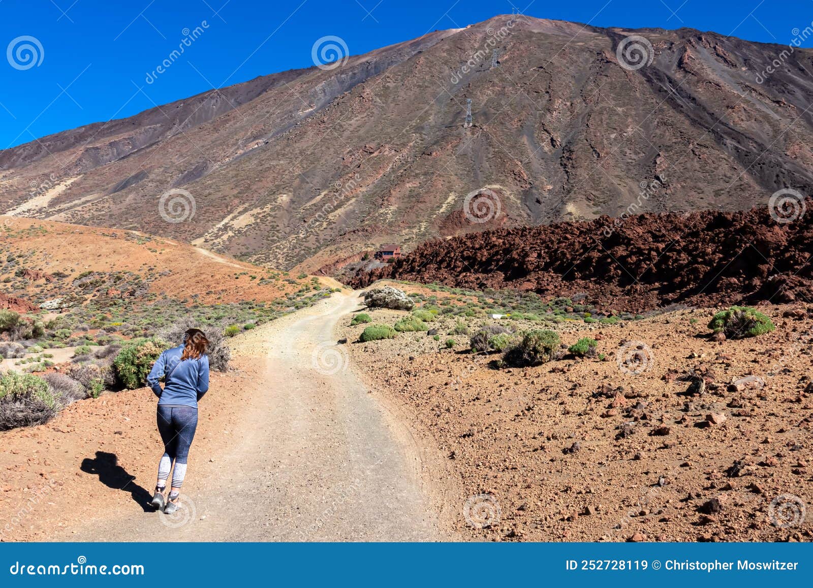 rear view on woman walking on panoramic hiking trail leading to pico del teide in volcano mount teide national park, tenerife