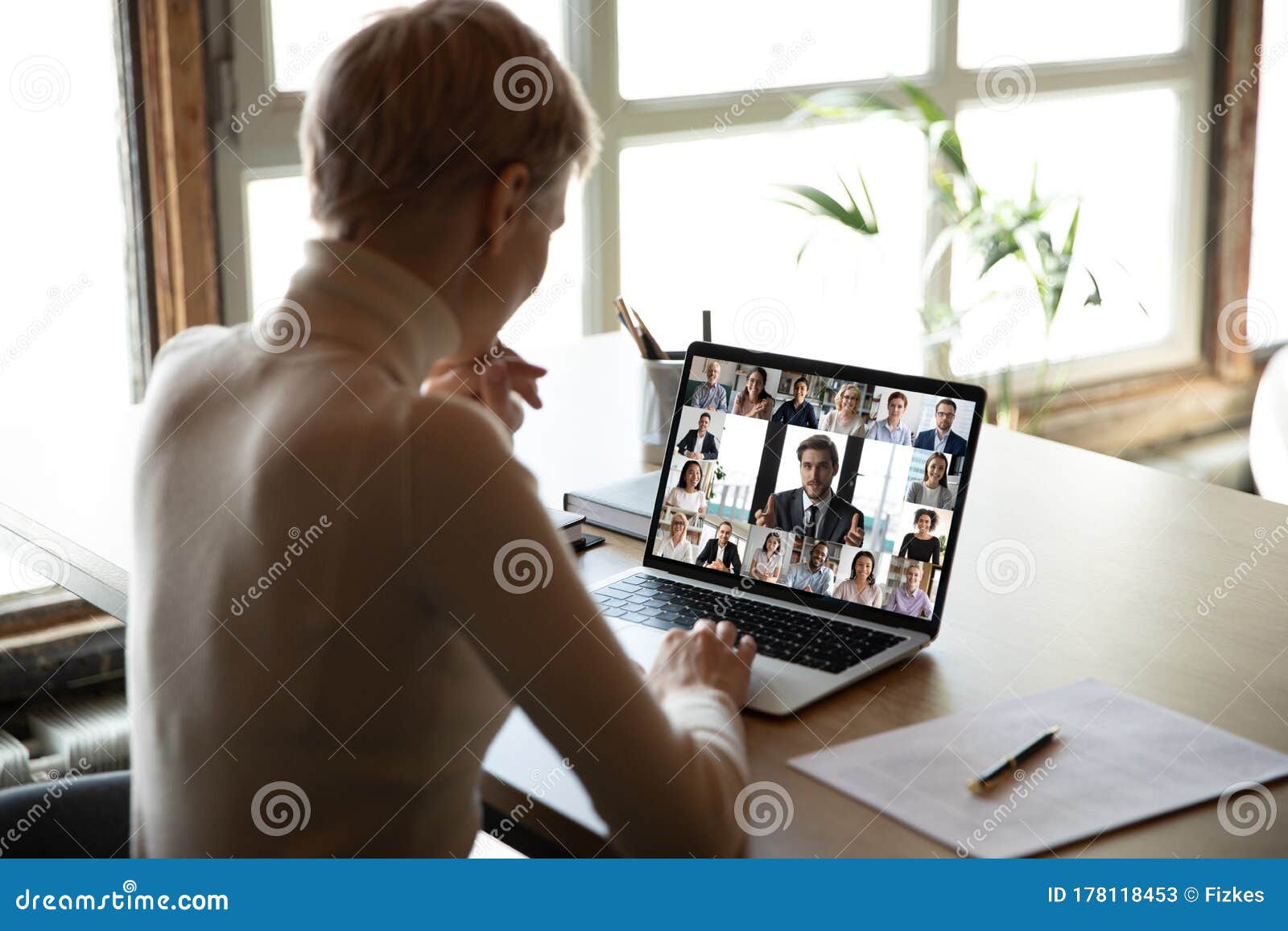 woman sitting at desk watching new videoconference application online review
