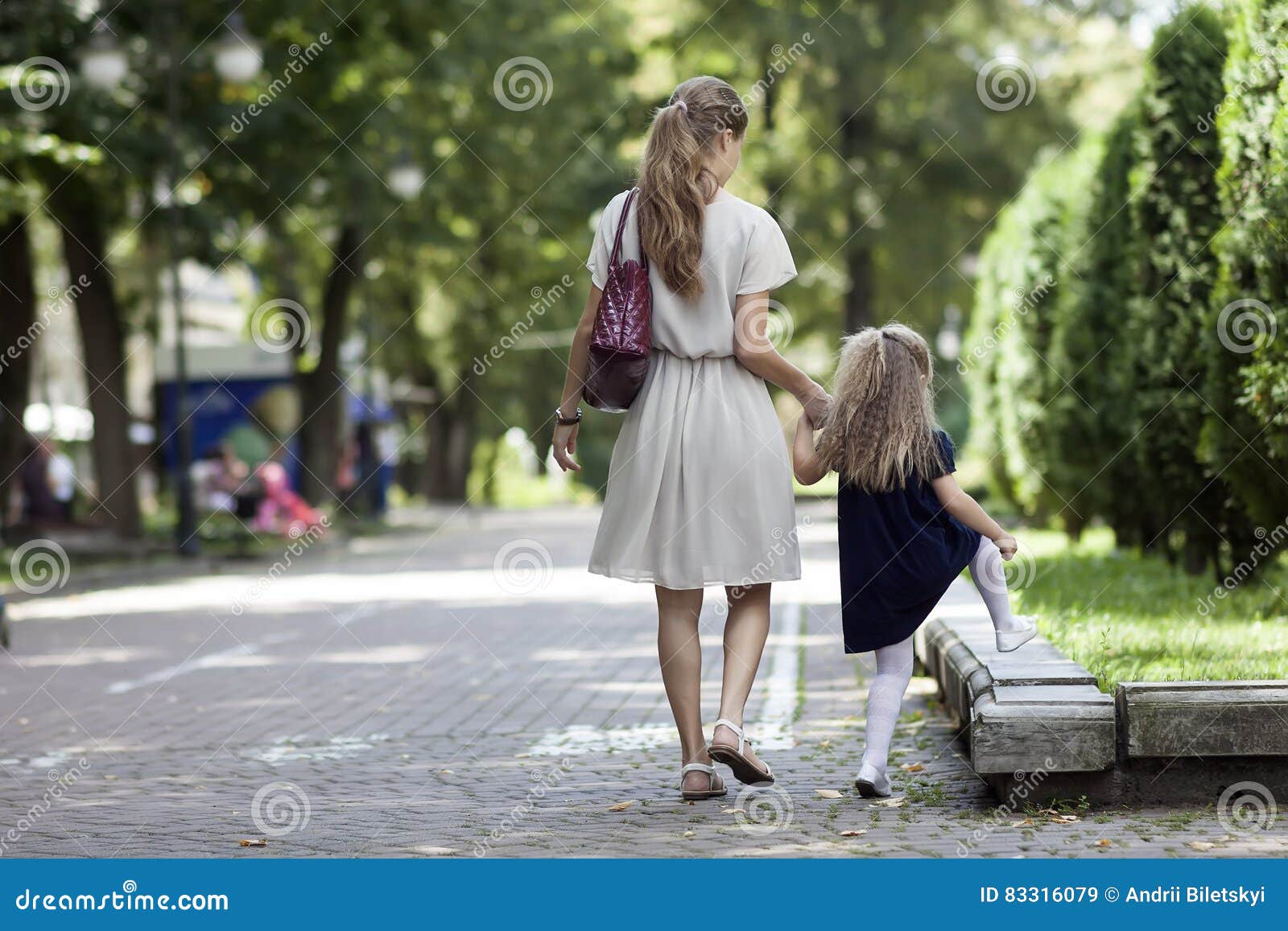 rear view of young mother walking with little girl daughter in