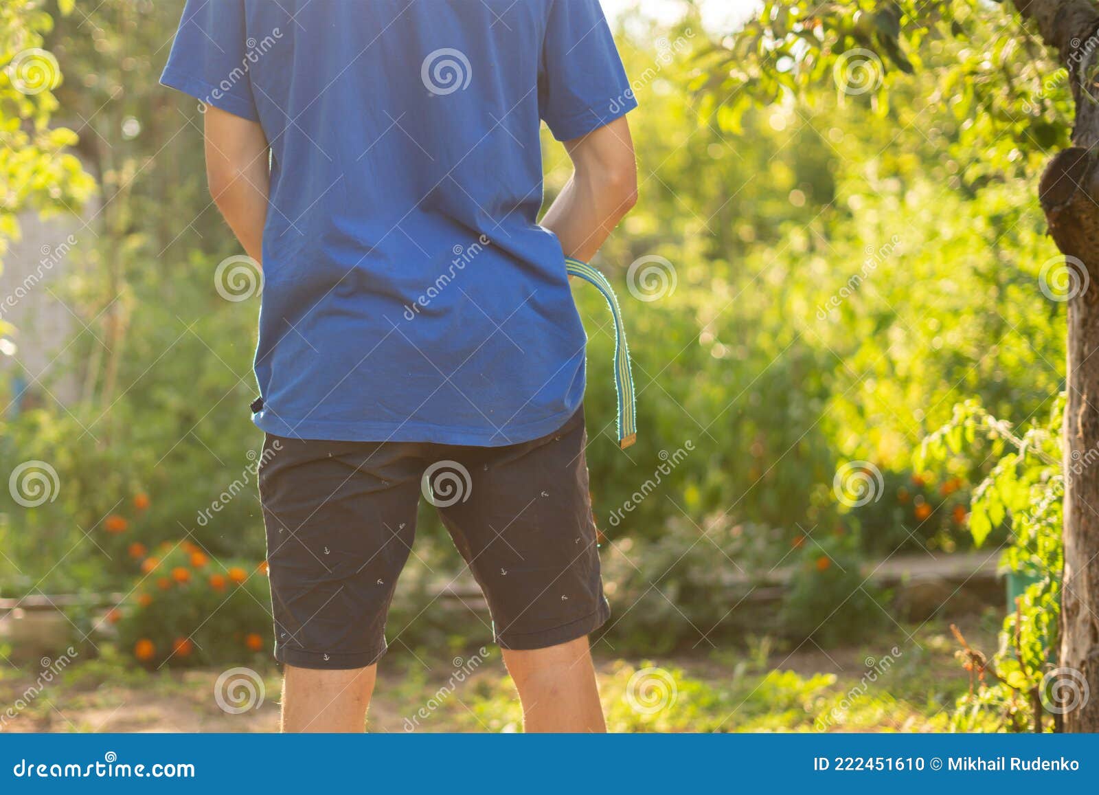 rear view of young person standing outdoor and piss under the trees