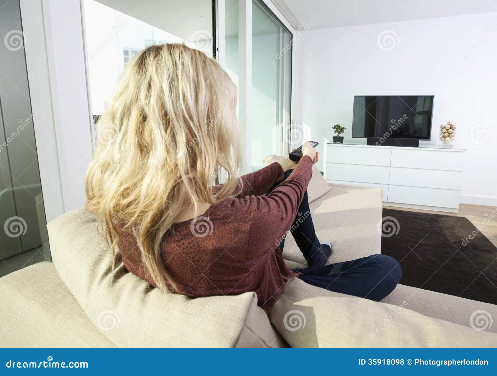 Rear View Of Young Woman Watching Television On Sof