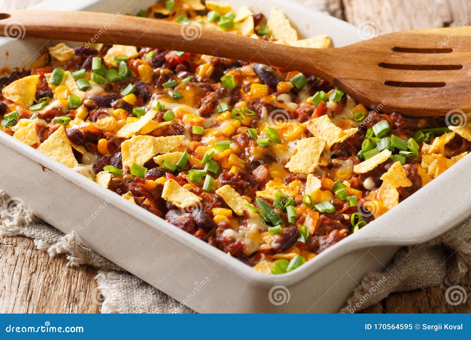 recipe for a delicious frito pie with ground beef, cheese, corn, beans and chips close-up in a baking dish. horizontal