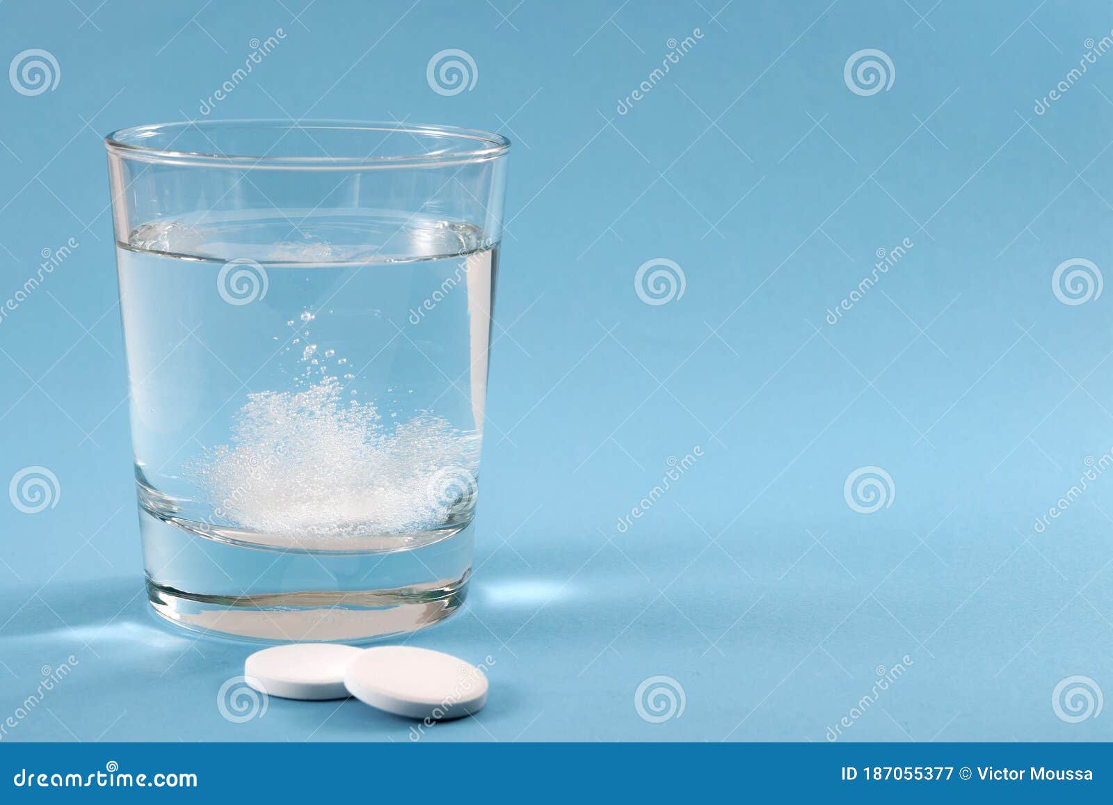 recovering from a hangover and nursing a headache with aspirin concept with effervescent drink tablet dissolving in water with two